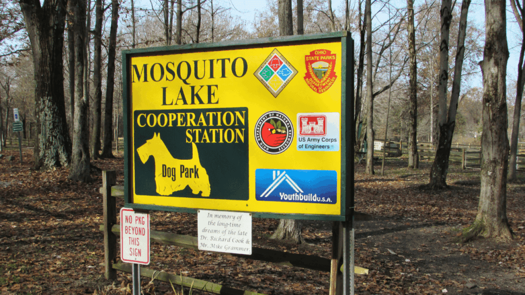 Entrance sign for Cooperation Station Dog Park at Mosquito Lake State Park in Northeast Ohio, surrounded by wooded trails and fenced areas