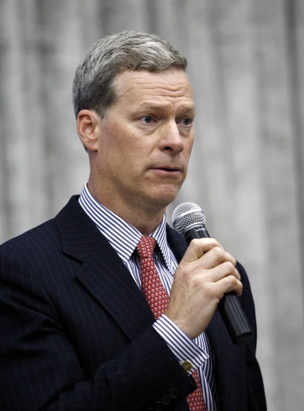 Steven C. Rockefeller Jr. speaking at a podium with microphone, wearing a suit and red tie, during a leadership or cultural arts event