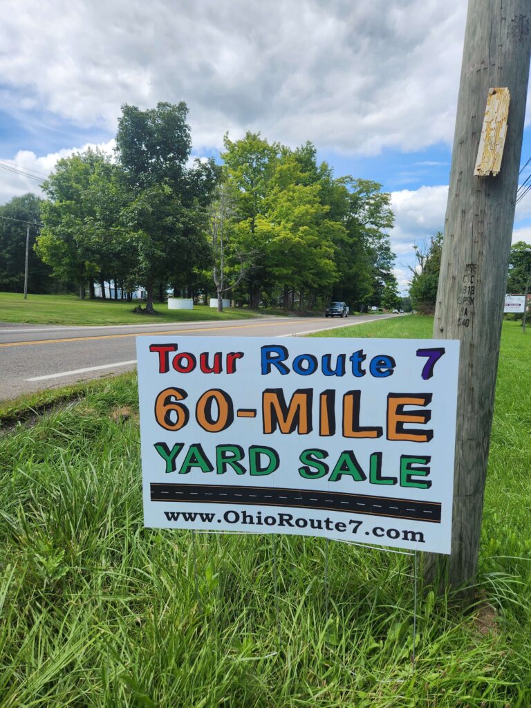 Route 7 60-Mile Yard Sale sign along scenic highway in Northeast Ohio, promoting Labor Day weekend treasure hunting.