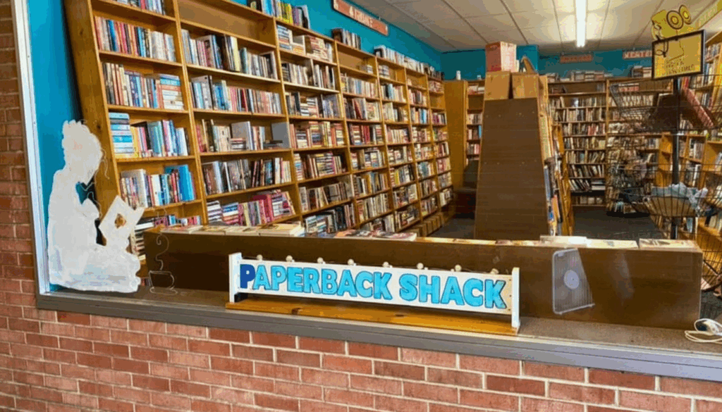 Storefront view into The Paperback Shack, a destination used bookstore in Niles near Youngstown, Northeast Ohio, with rows of wood shelves packed with paperbacks.