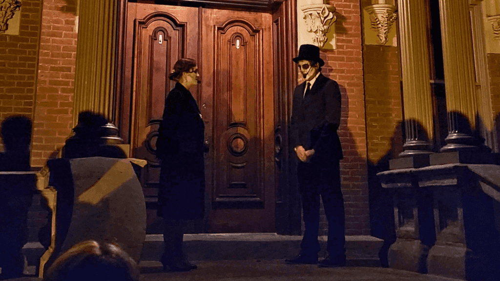 Two costumed performers share a ghost story on the steps of a historic brick building during the Warren Ghost Walk in downtown Warren, Ohio.
